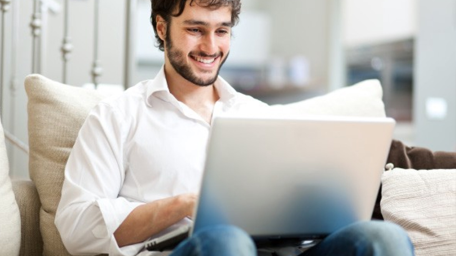 Un hombre sonríe mientras realiza su empleo en una laptop