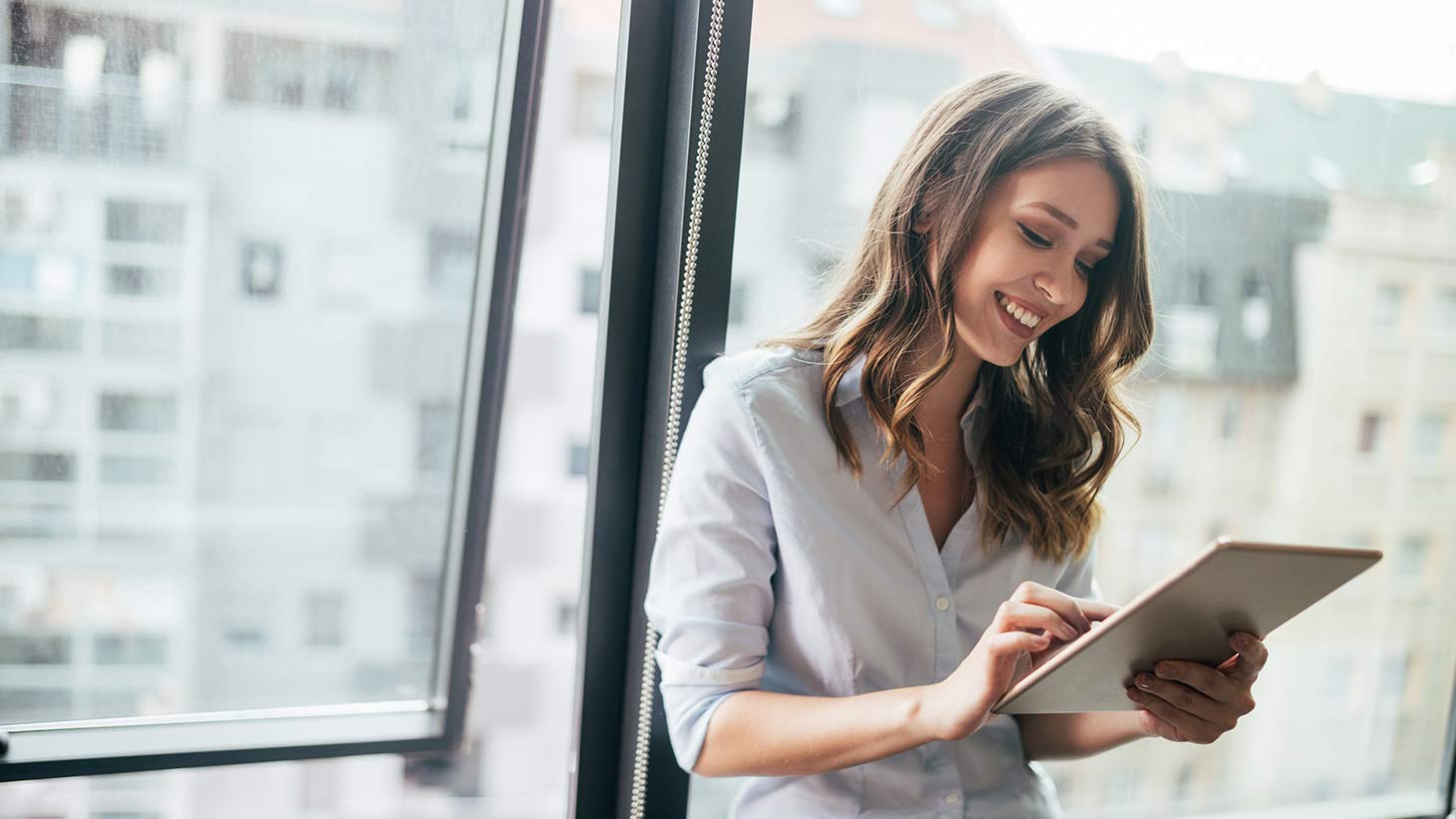 Una mujer sonríe y utiliza una tablet en su empleo. 